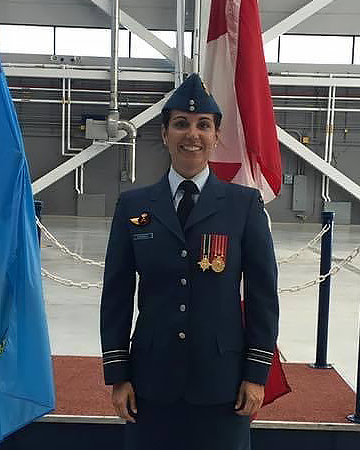 Jan Kennedy in uniform standing in front of Canadian flag