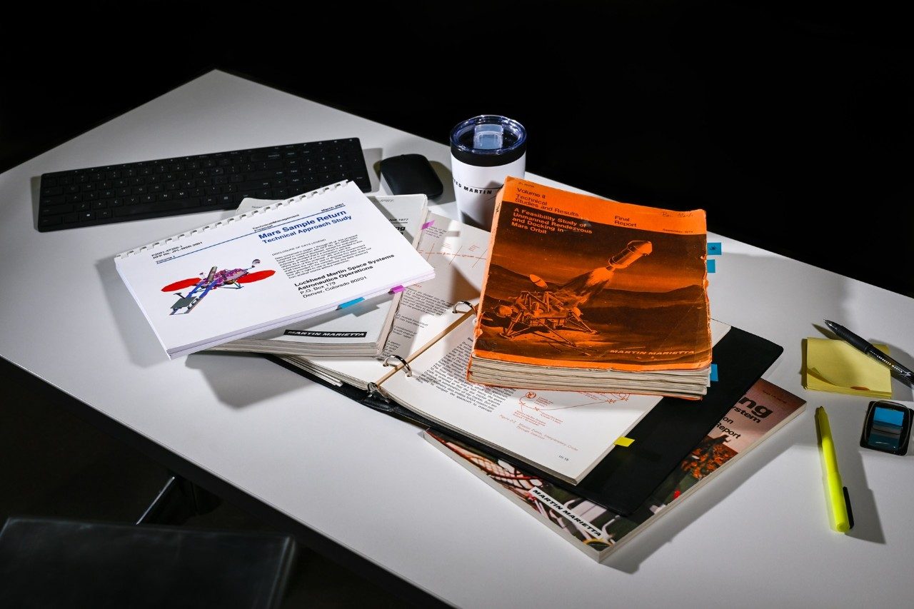 Photo of various Lockheed Martin Mars Sample Return studies and proposals over 50 years on a desk